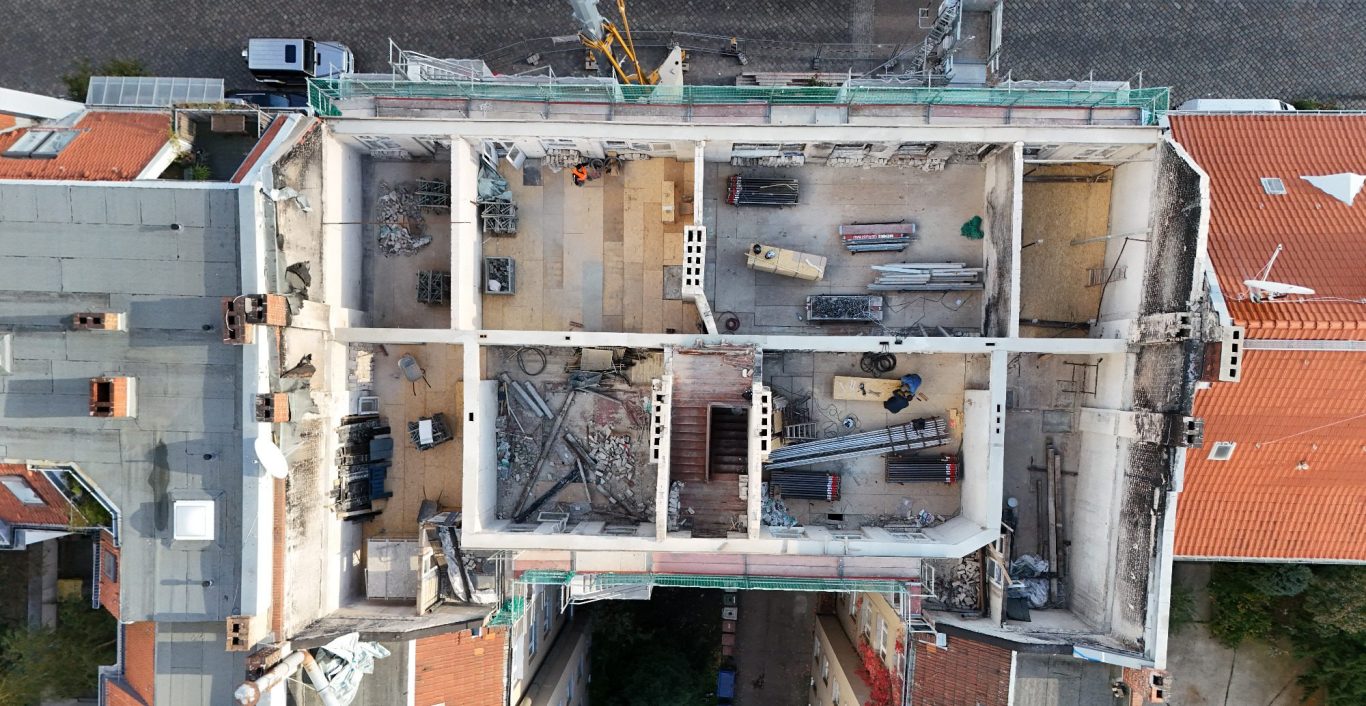 Luftaufnahme Sanierung Mehrfamilienhaus Berlin Blick von oben auf eine Baustelle mit Baumaschinen von einem Mehrfamilienhaus in Berlin.